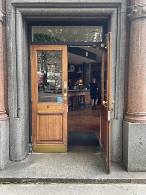 Double brown wooden door with glass panel. Pull golden knob on left of right door to open.