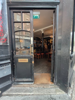 From right of venue facing left. Black framed door to main area. Push golden metal handles in centre to open.