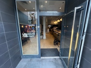 Grey framed glass door. Pull open via long silver handle on left hand side.