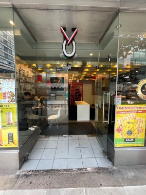 Double glass doors set back from pavement. Pull long silver metal handle from centre to open.