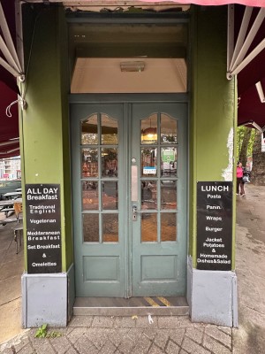Green and glass panelled double doors. Silver handle to right of left-hand door. Push to open.