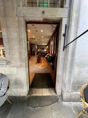 Brown wooden door. Push open via handle on left.