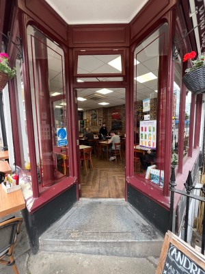 2 steps up to red framed glass door ahead. Push open via handle on right.