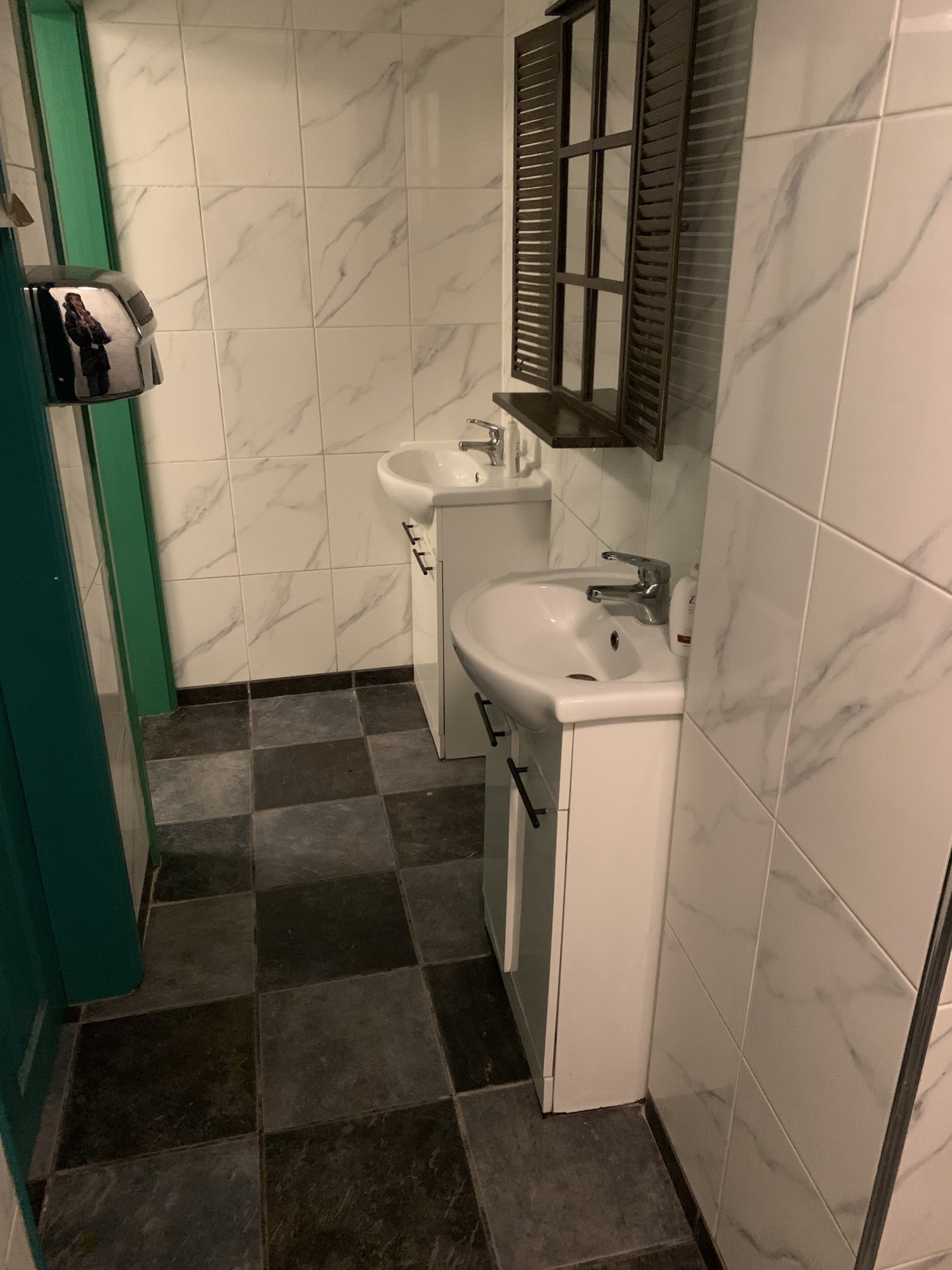 Sinks on the right through the open doorway, with bathroom cubicles opposite.