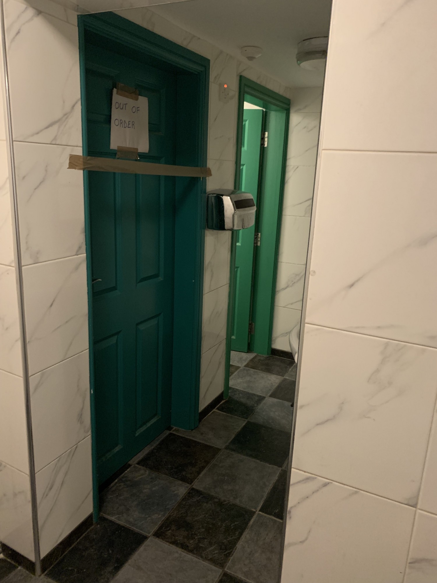 Open doorway right and right again from the first door, with bathroom cubicles on the left.