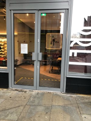 Glass doors with grey framing ahead. Push handles in centre to open.