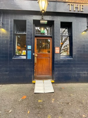 Facing venue entrance. Ramp upon request at bottom. Wooden door with push to open knob on left.