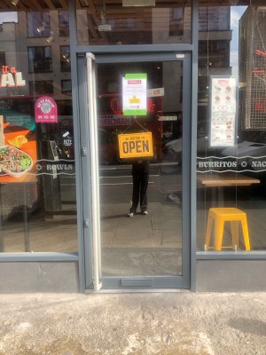 Metal-framed glass door. Push from silver handle on left to open.