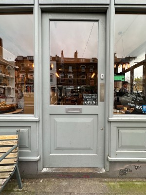 Glass door with grey wooden frame. Push from right to open.