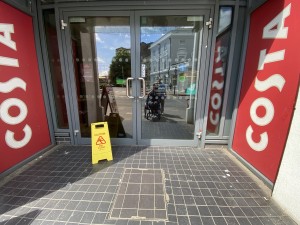 Glass doors with grey frames ahead. Pull from handles in centre to open