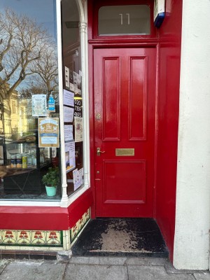 One step up to landing before red wooden door. Handle at left. Rotate and push to open