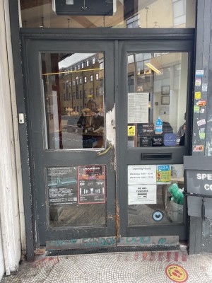 View of the front entrance from the street. This is situated to the left of the venue front. There is a set of double doors, however the left one is primarily in use. The left door pushes open from the right. There is a built in ramp leading from the street up to the foot of the door.
