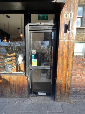Glass door with black frame ahead. Push black metal handle on left to open.