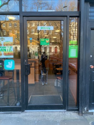 Glass door with black metal frame ahead. Push from black handle on left to open.
