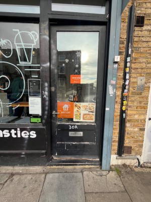 Glass door with black wooden frame and metal handle on left. Push to open.