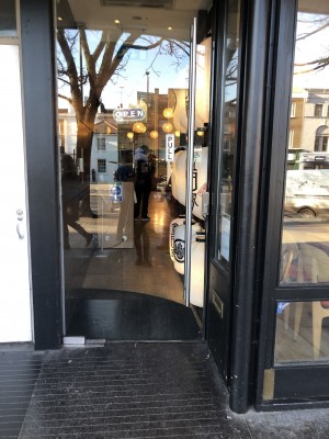 Glass door ahead with silver handle on right. Pull to open.