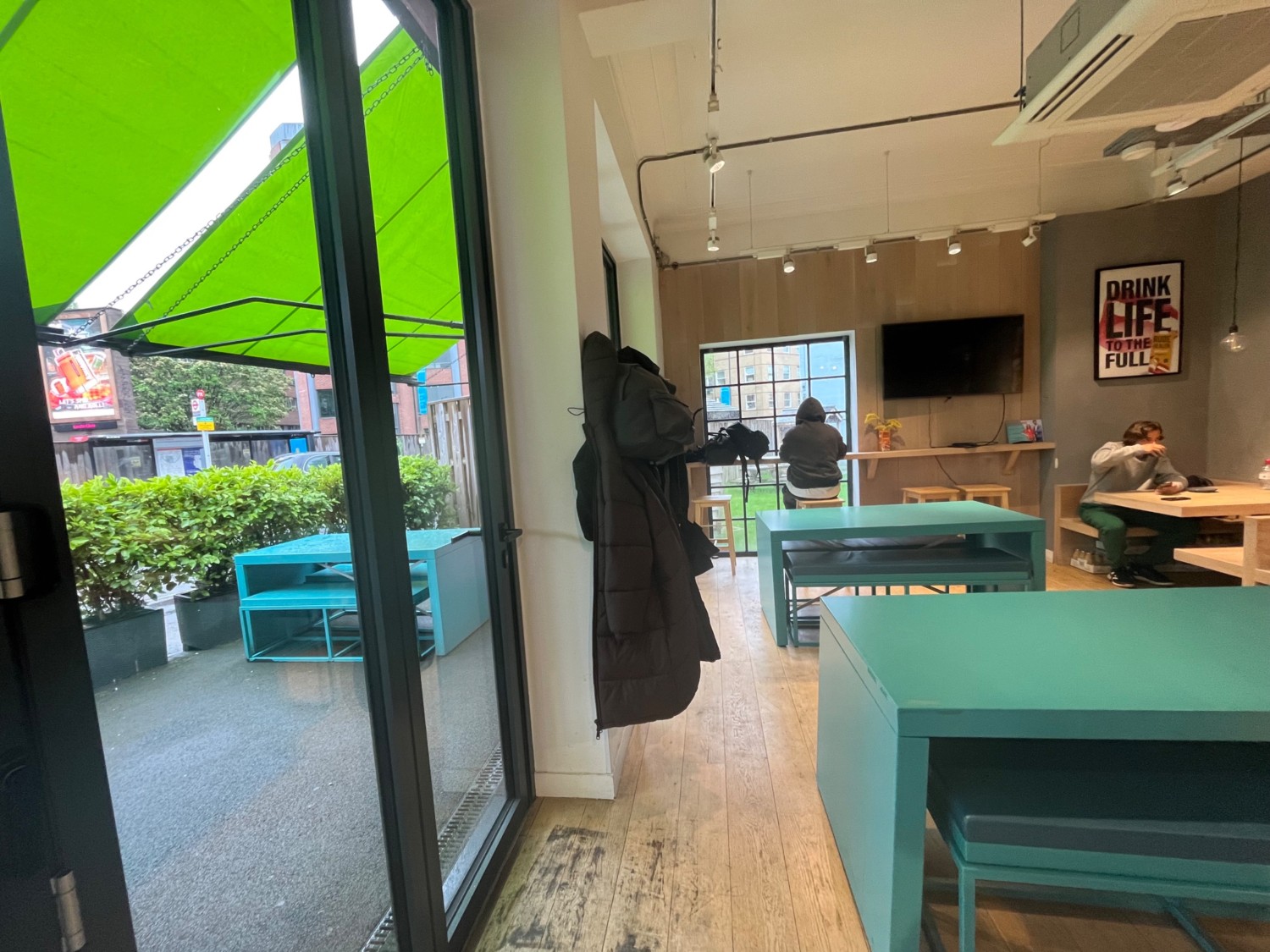 From left path facing straight. Path straight. Tables and benches right. High table and stools at end of path.
