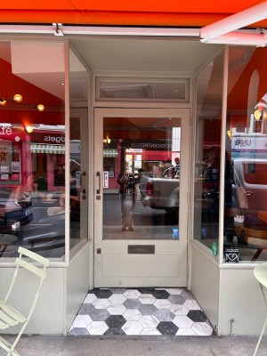 Archway ahead. Glass door with white frames at back. Pull from left to open.