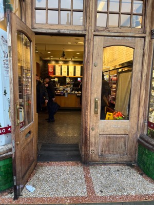 Glass door with brown, wooden frame. Pull golden handles in middle to open.