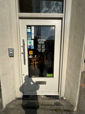 White and glass panelled door with silver vertical handle to left of door. Push to open.
