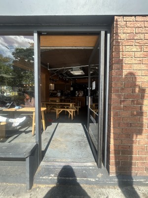 Glass door ahead with black frame. Push black handle on left to open.