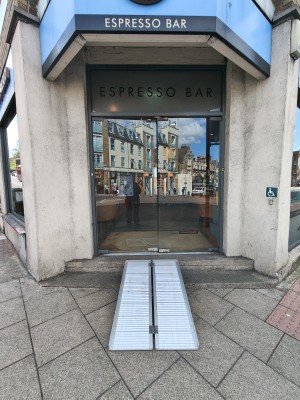 Ramp upon request up to glass doors. Push silver handles in centre to open. Doorbell for assistance on right of doors.
