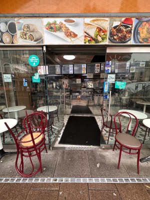 Glass door ahead. Push silver handle on right to open. Tables and chairs to left and right of door.