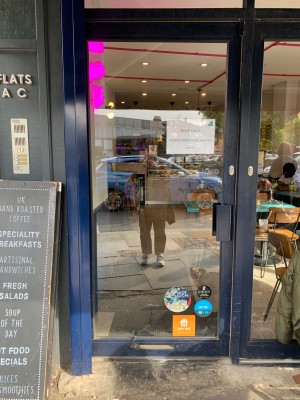 Glass door with blue metal frame ahead. Push handle on right to open.