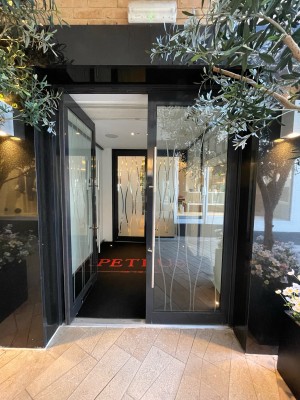 Metal-framed glass door. Push from metal handle at centre to open.