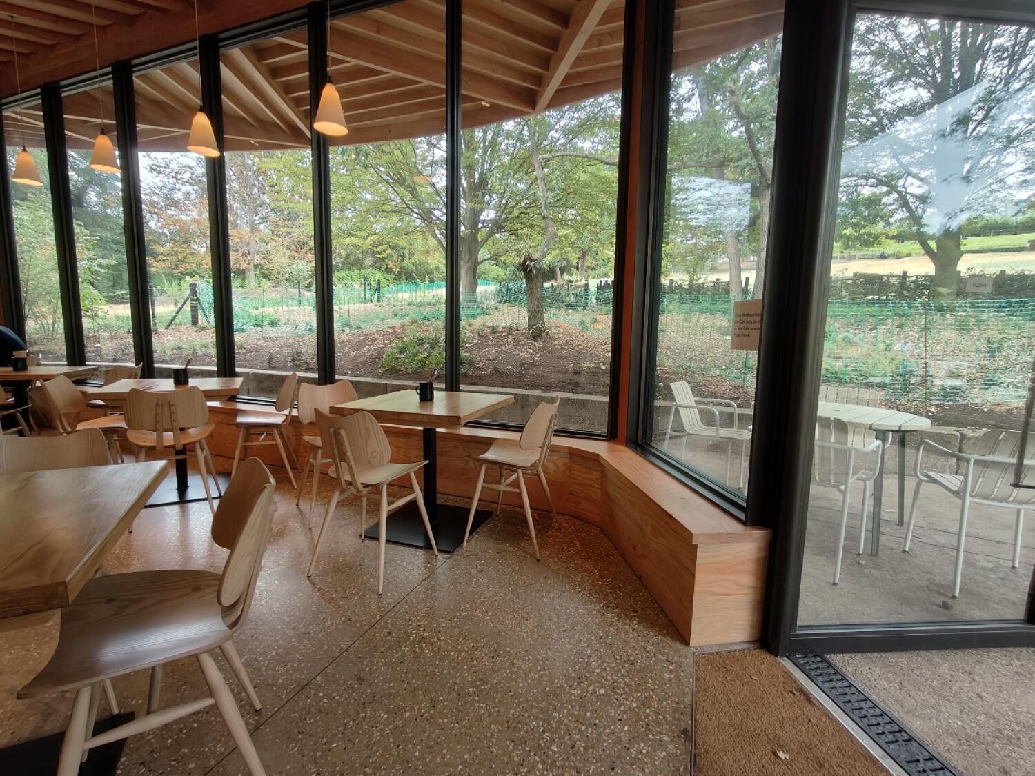 Tables and chairs on left. Tables and chairs in centre. Glass door on right.
