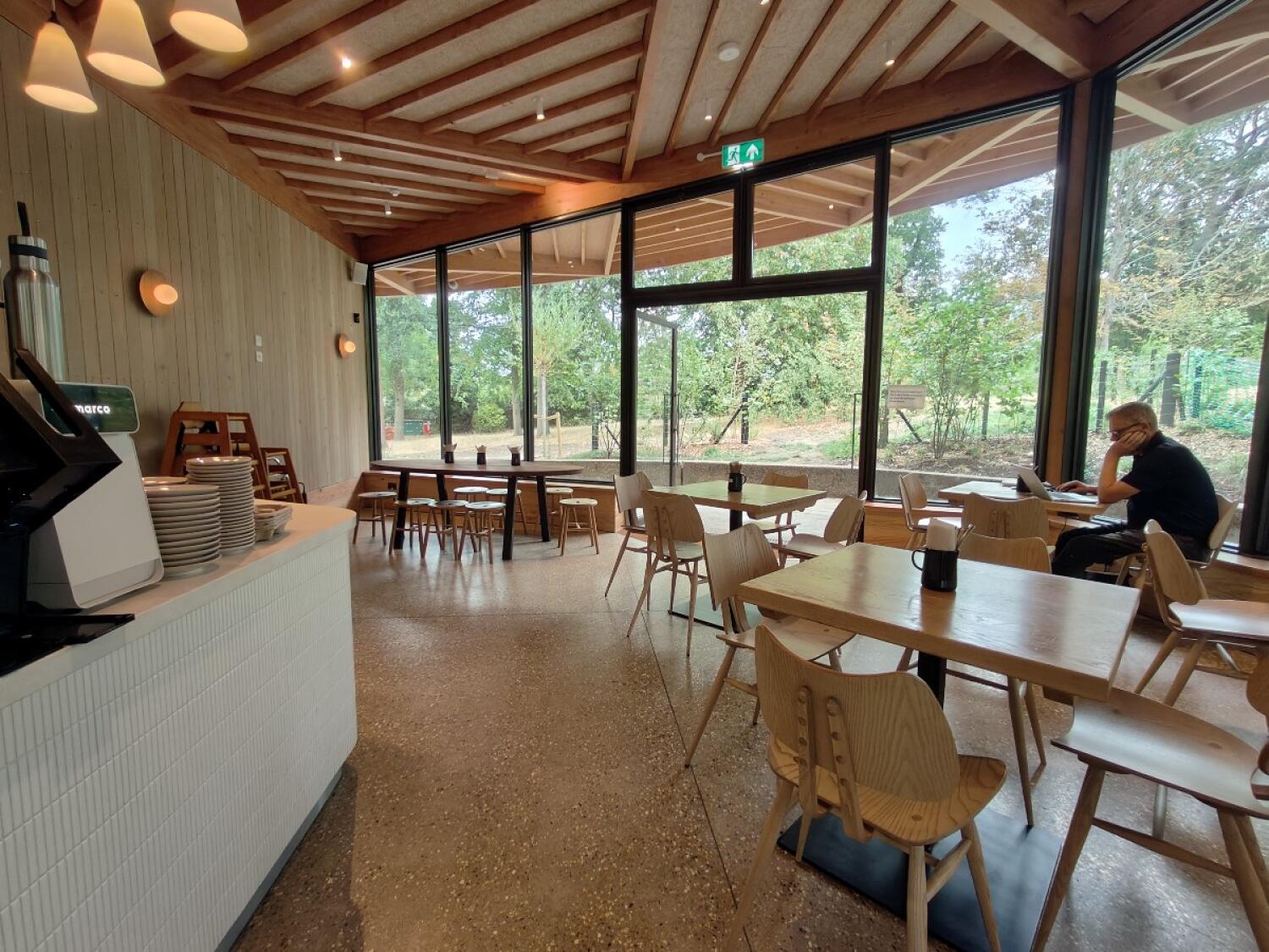 Counter along left. Tables and chairs in centre. Tables and chairs along right.