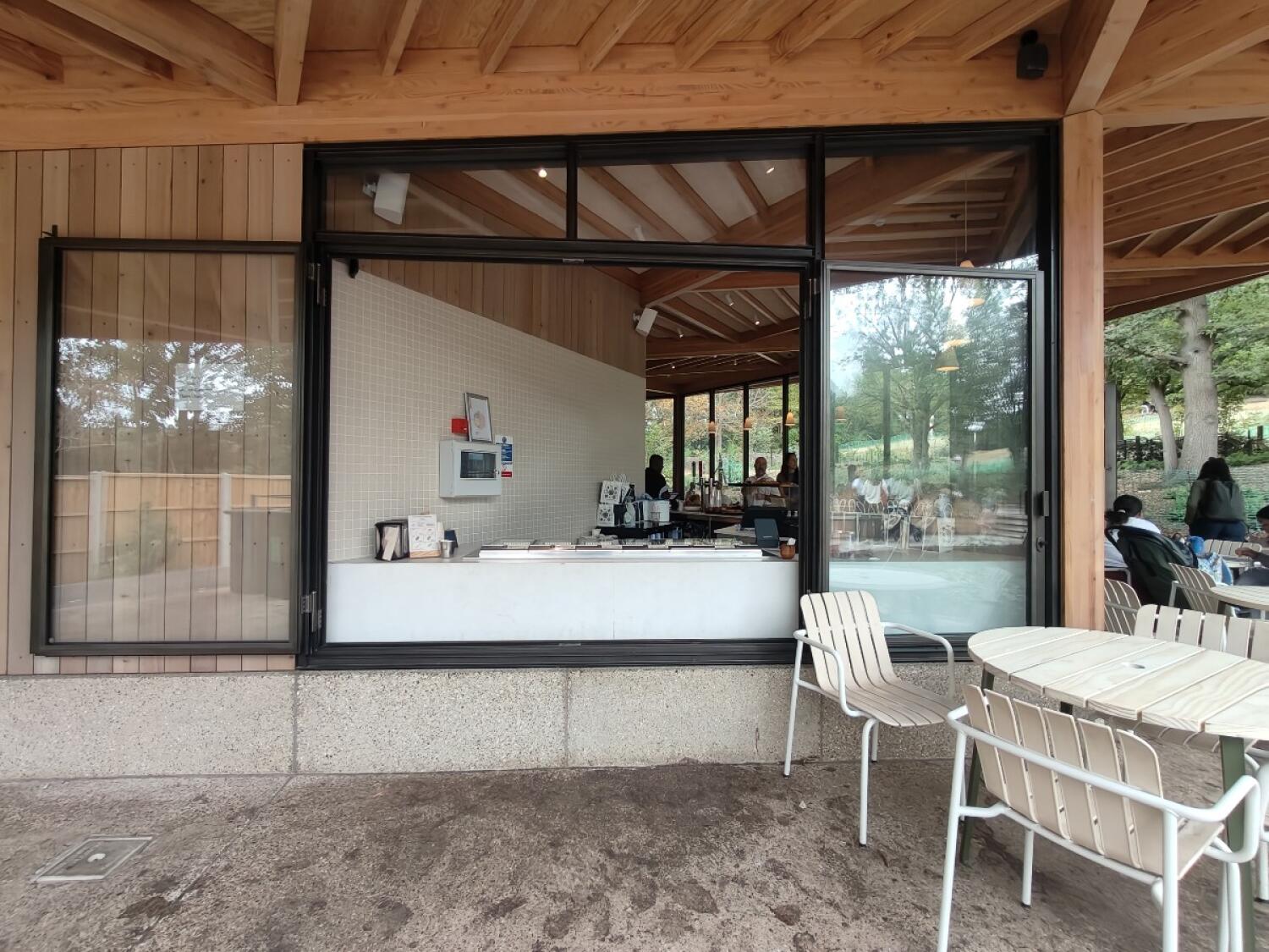 Service counter in centre. Glass door on right. Tables and chairs on right.