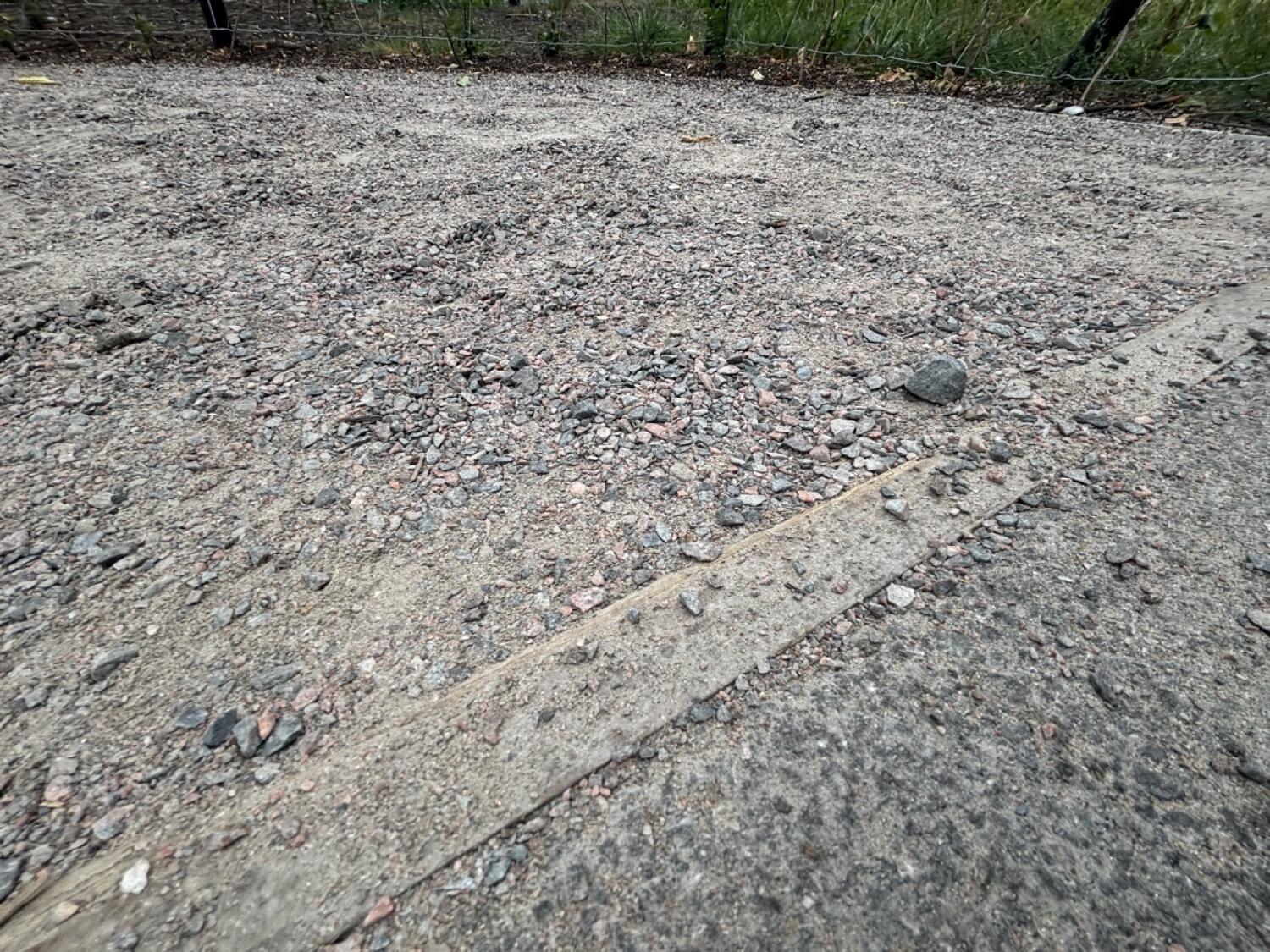 Uneven gravel path with concrete strip across foreground.
