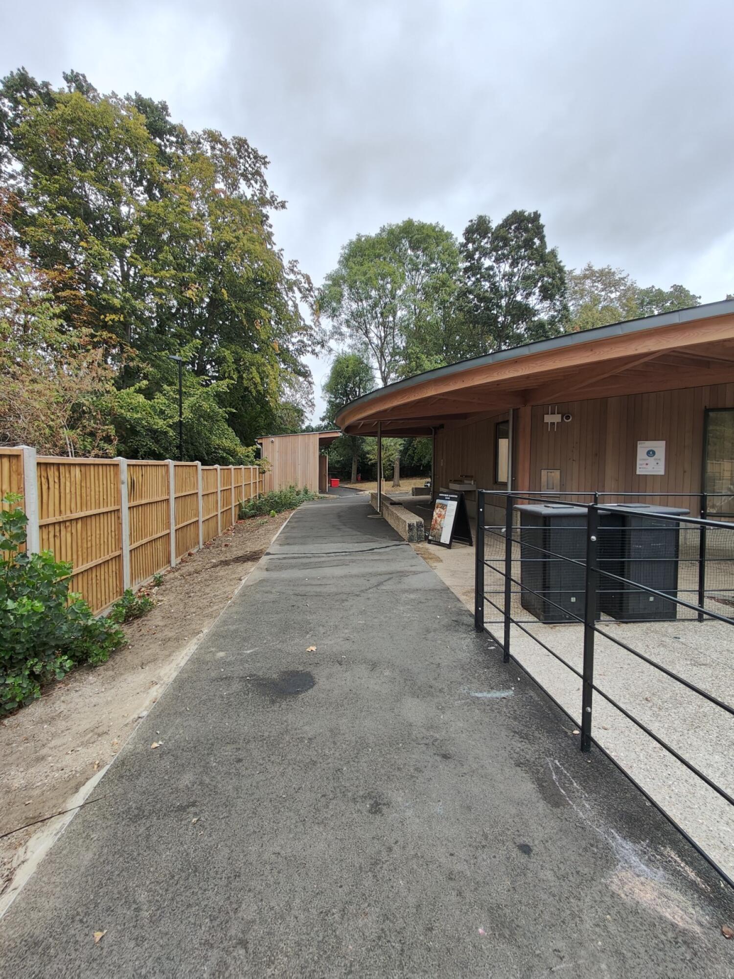 Path ahead, building on right and fence on left.