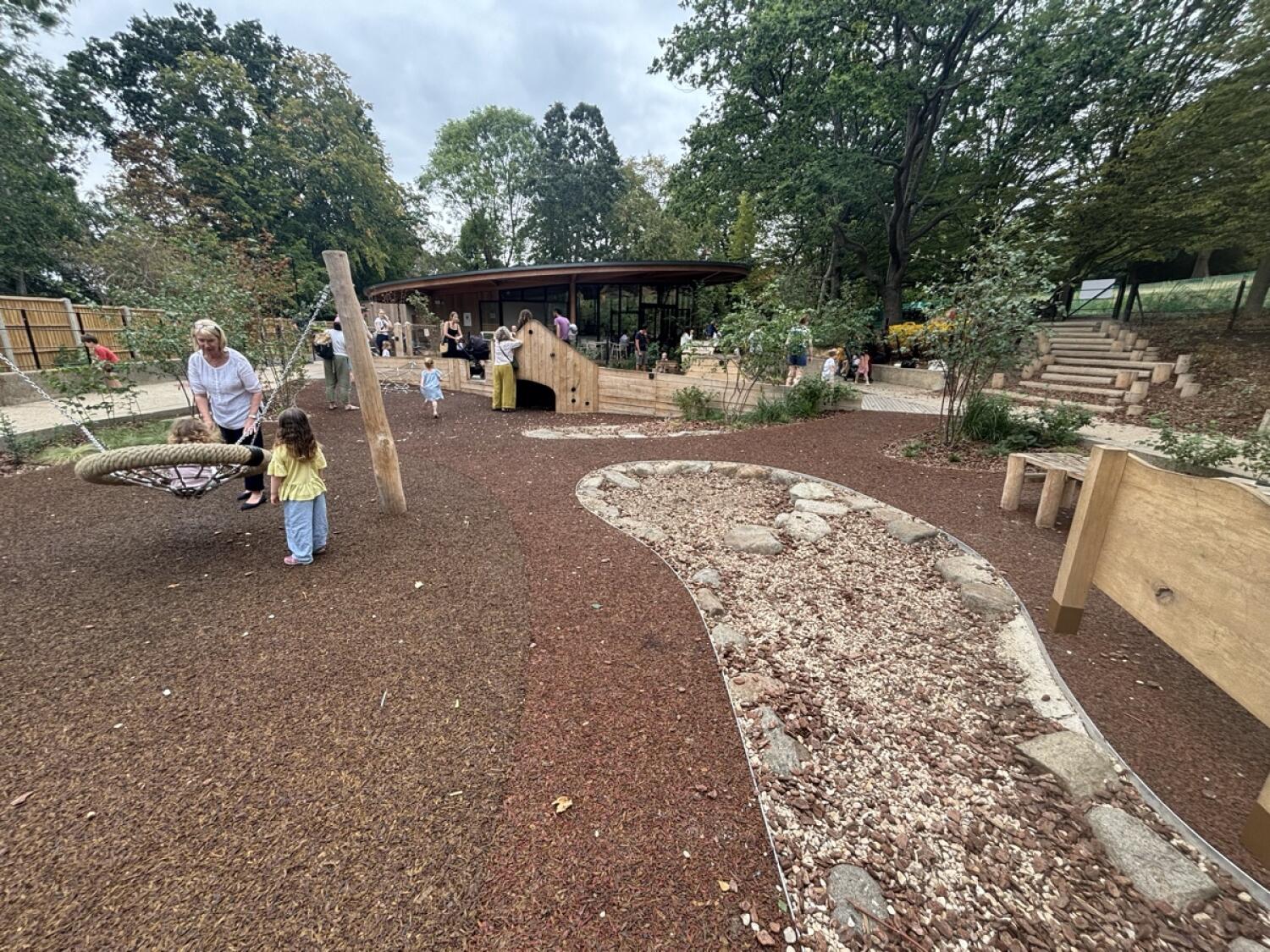 From bottom of steps facing straight. Basket swing on left. Gravel play area on right.