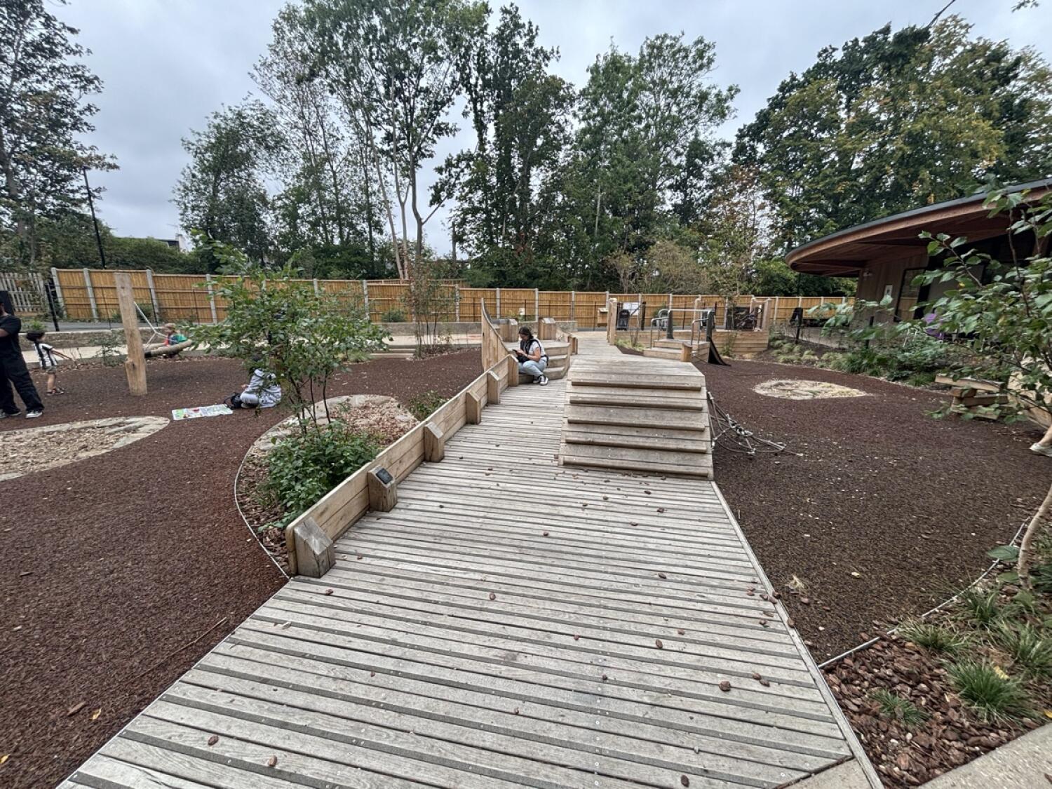 From opening on right facing straight. Wooden path ahead with climbing posts at back right.