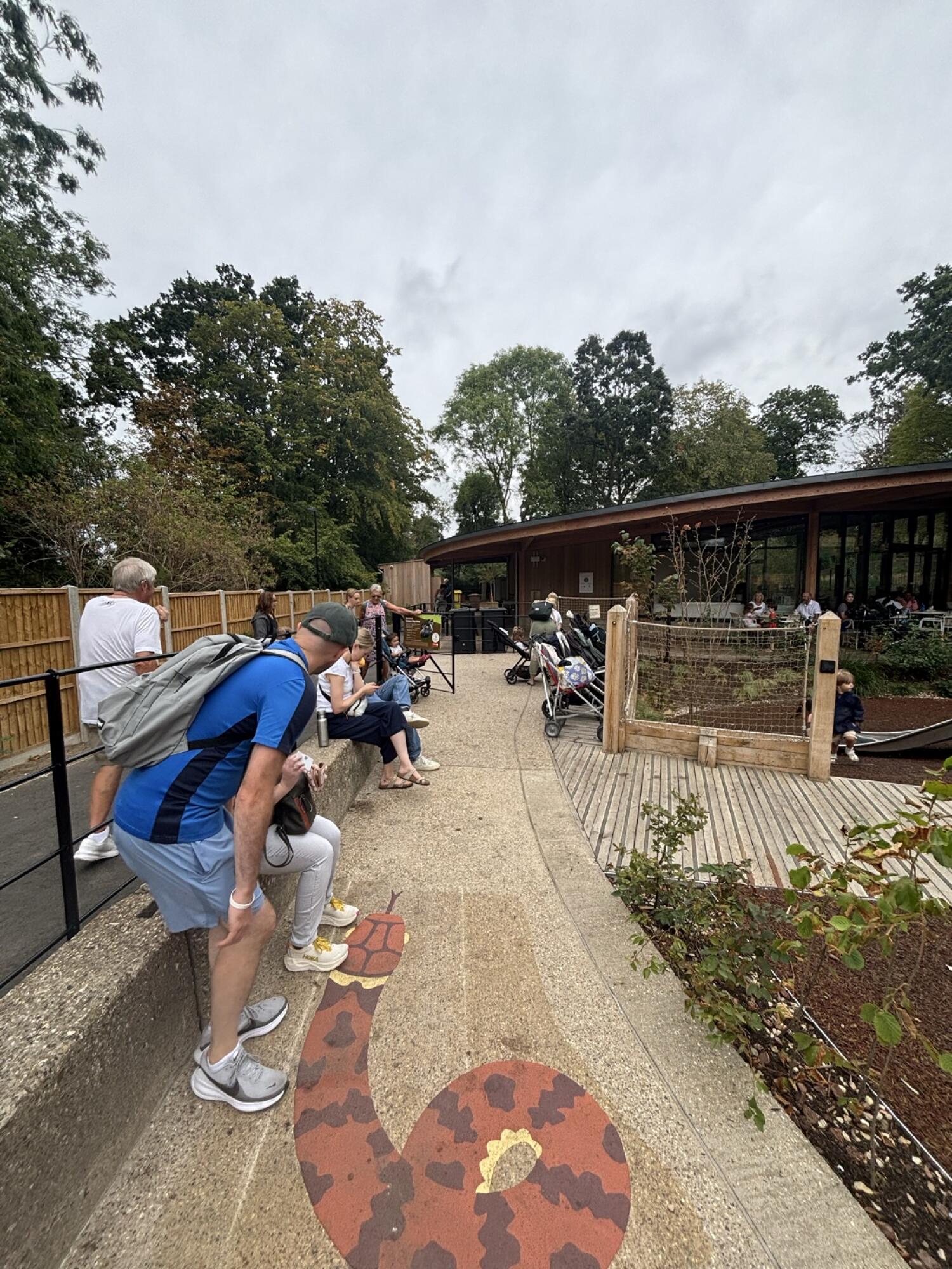 From end of curved path facing straight. Fixed benches along left. Path ahead to buggy parking space at back right.