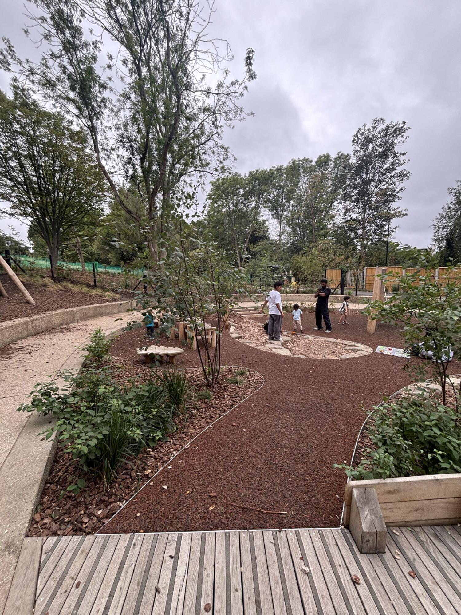 From opening facing left. Path ahead to gravel play area. Plant beds on left and right.