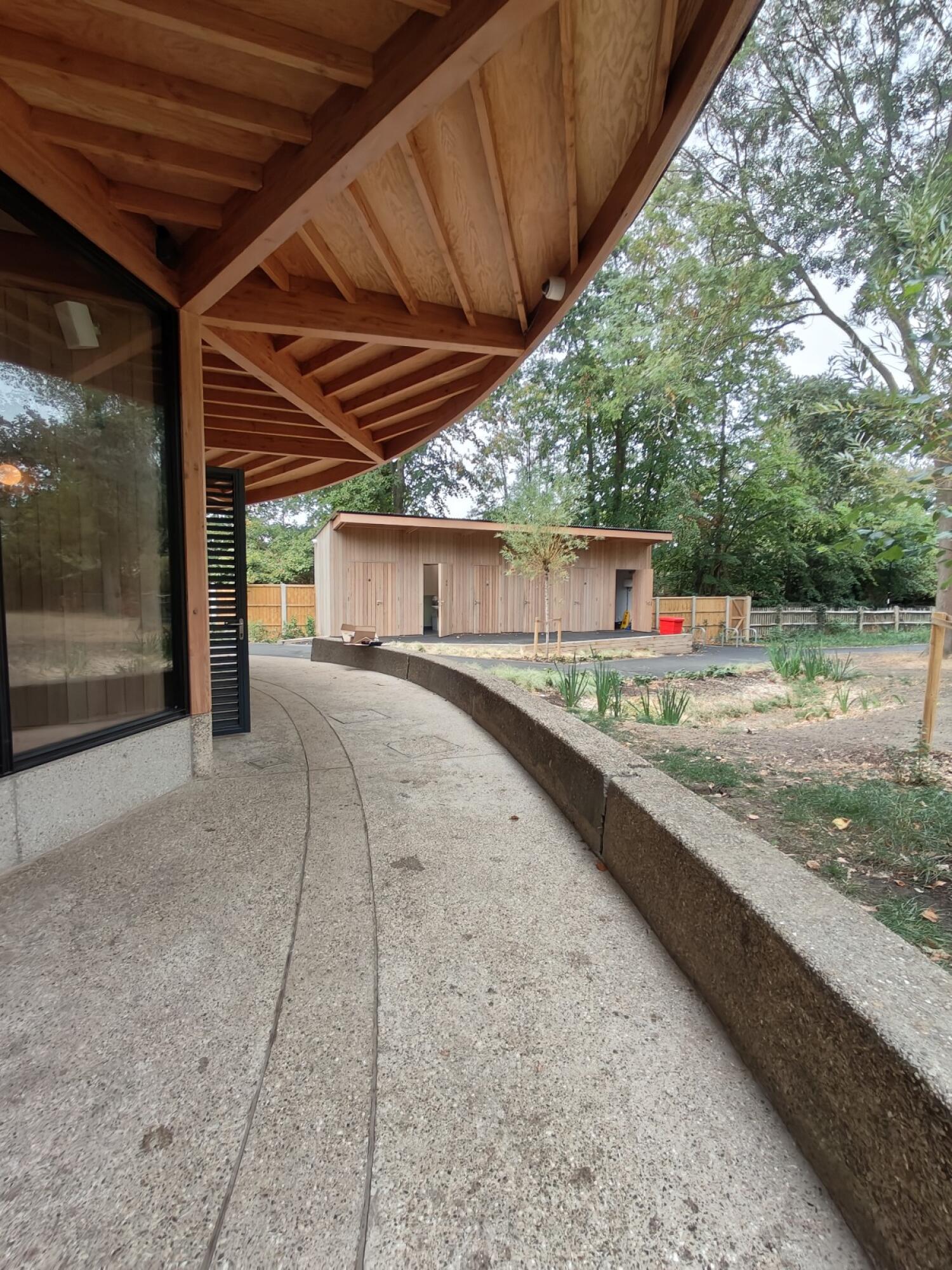 Curved path along building, low wall on right.