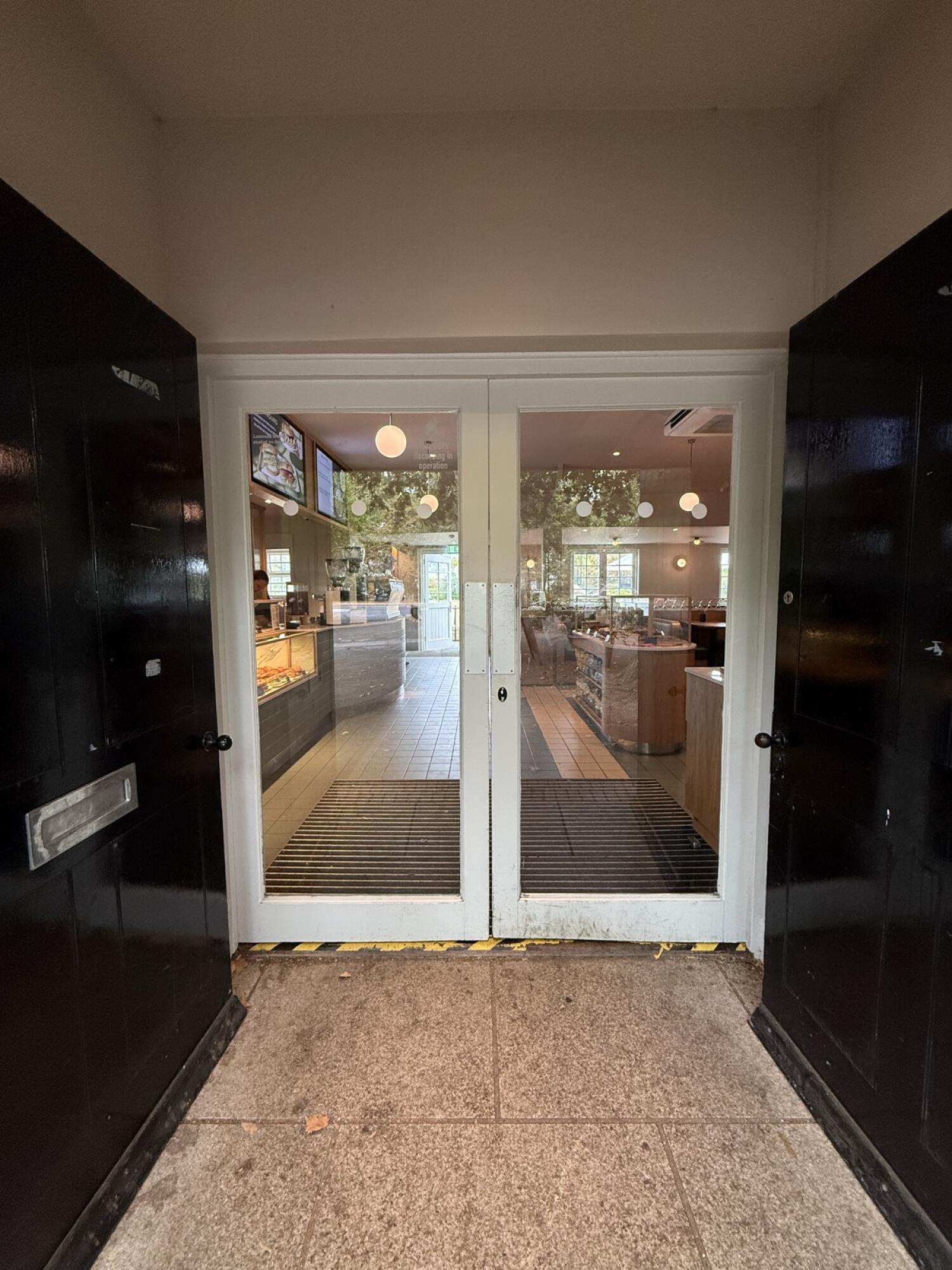 From door facing straight. White wood-framed glass doors. Use handles to open.