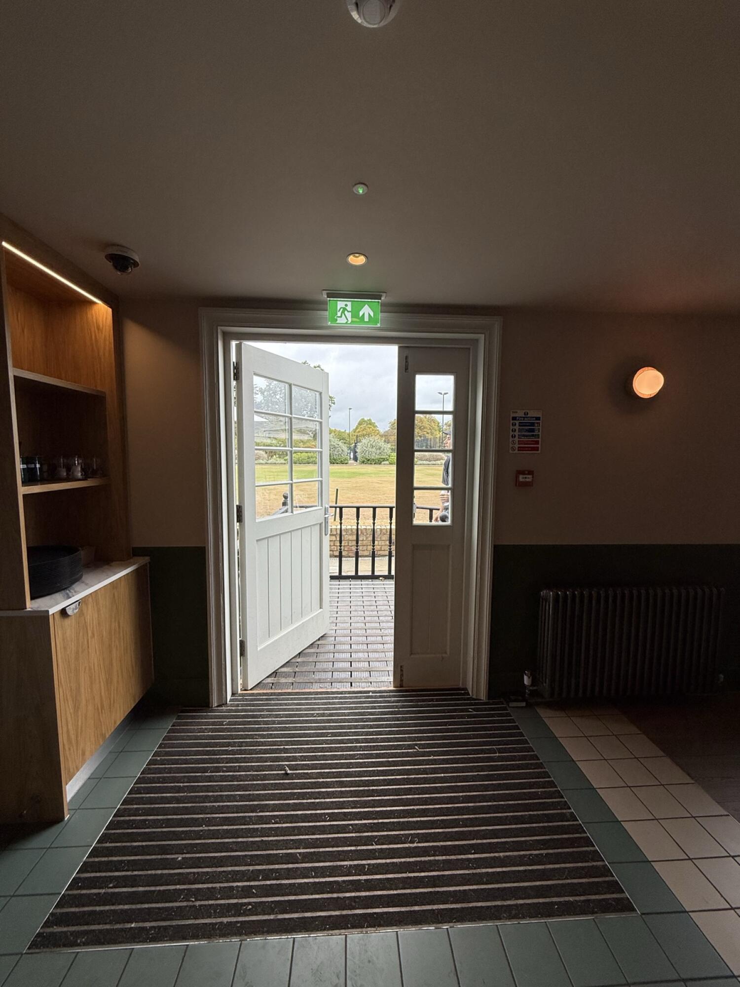 From side area facing straight. White wood-framed glass doors. Push from handle to open.