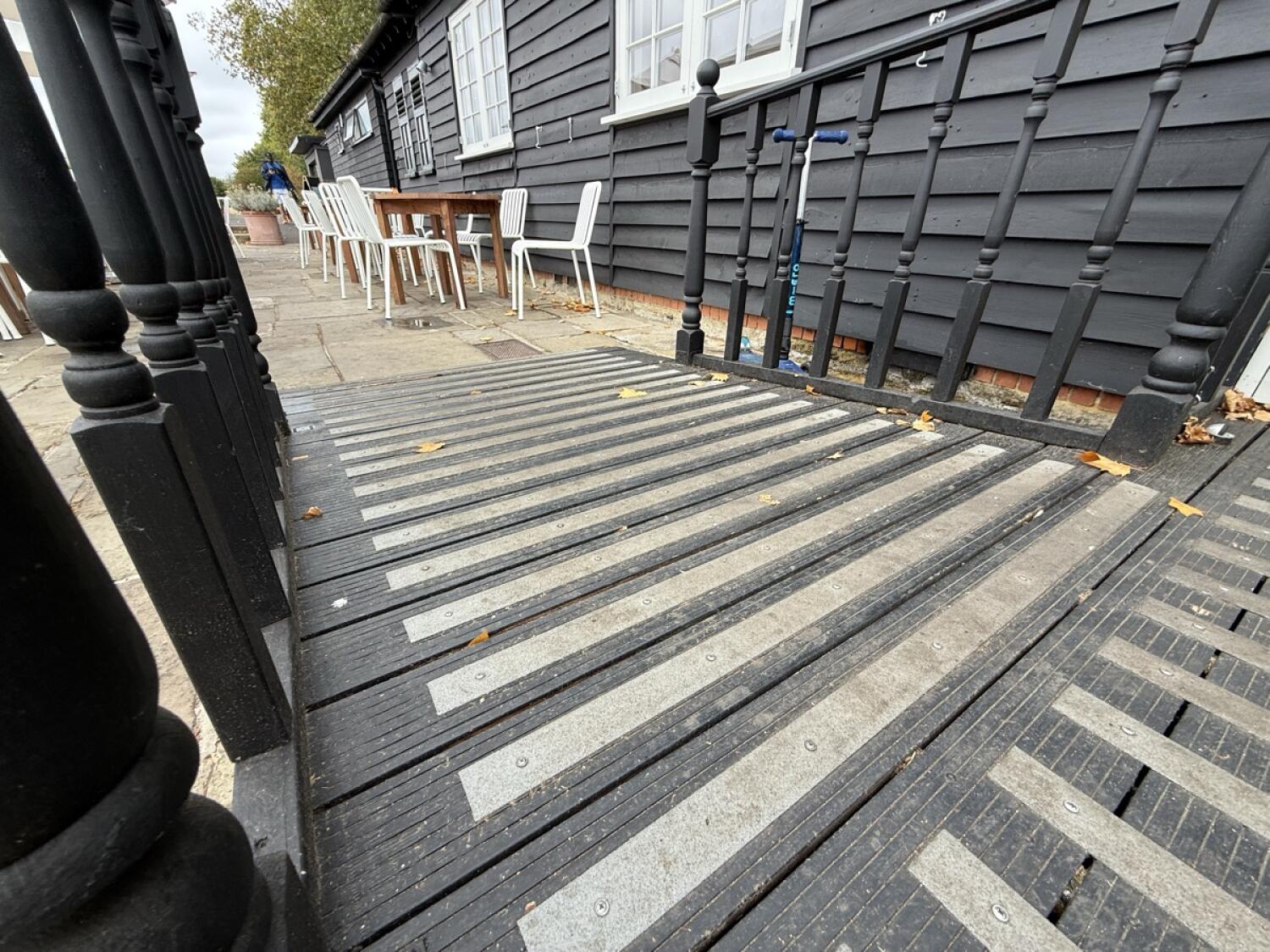 Ramp down, handrails on left and right. Tactile grip along ramp.