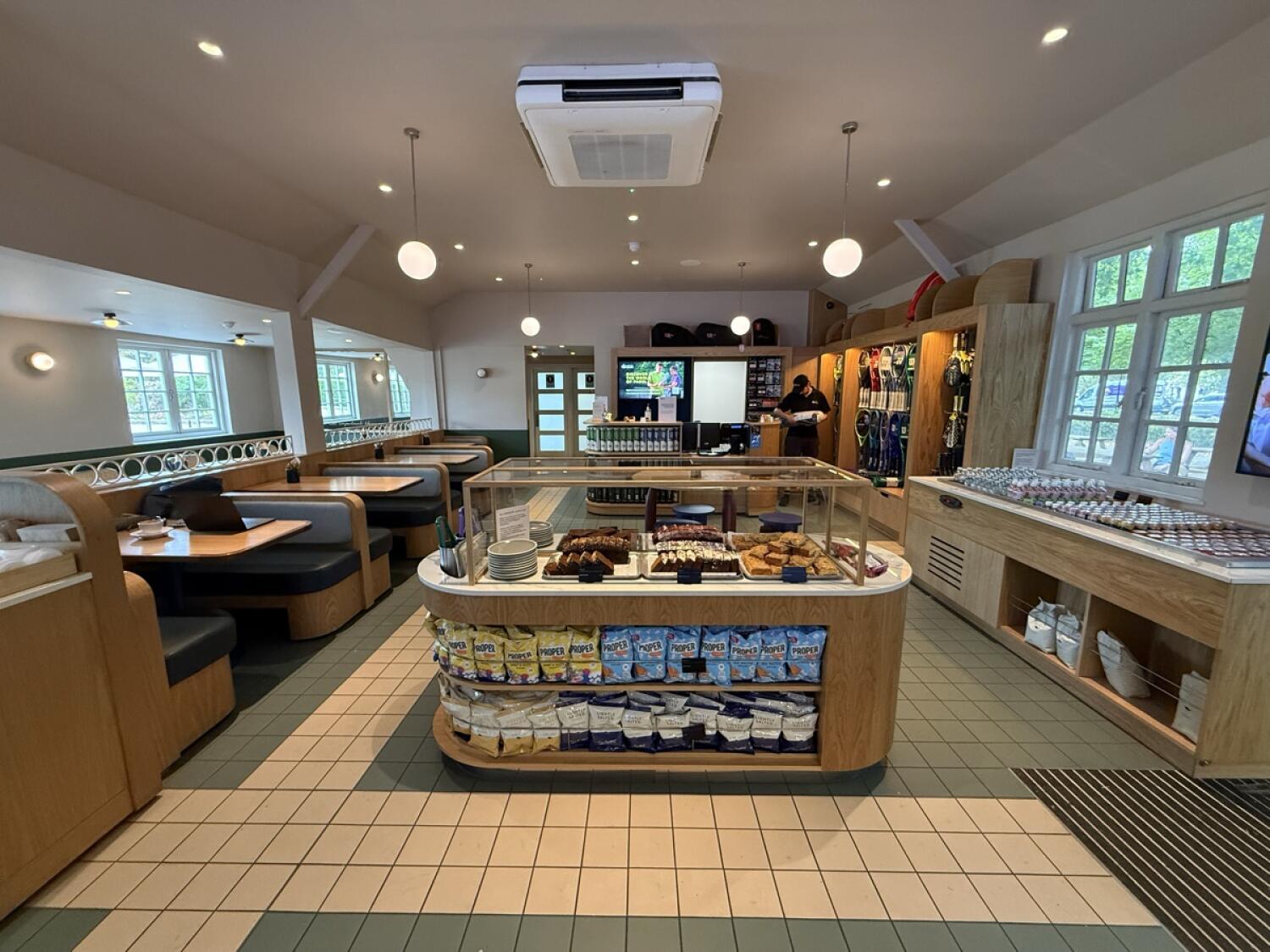 From entrance facing right. Booths along left. Display counter in centre. Product shelves right.