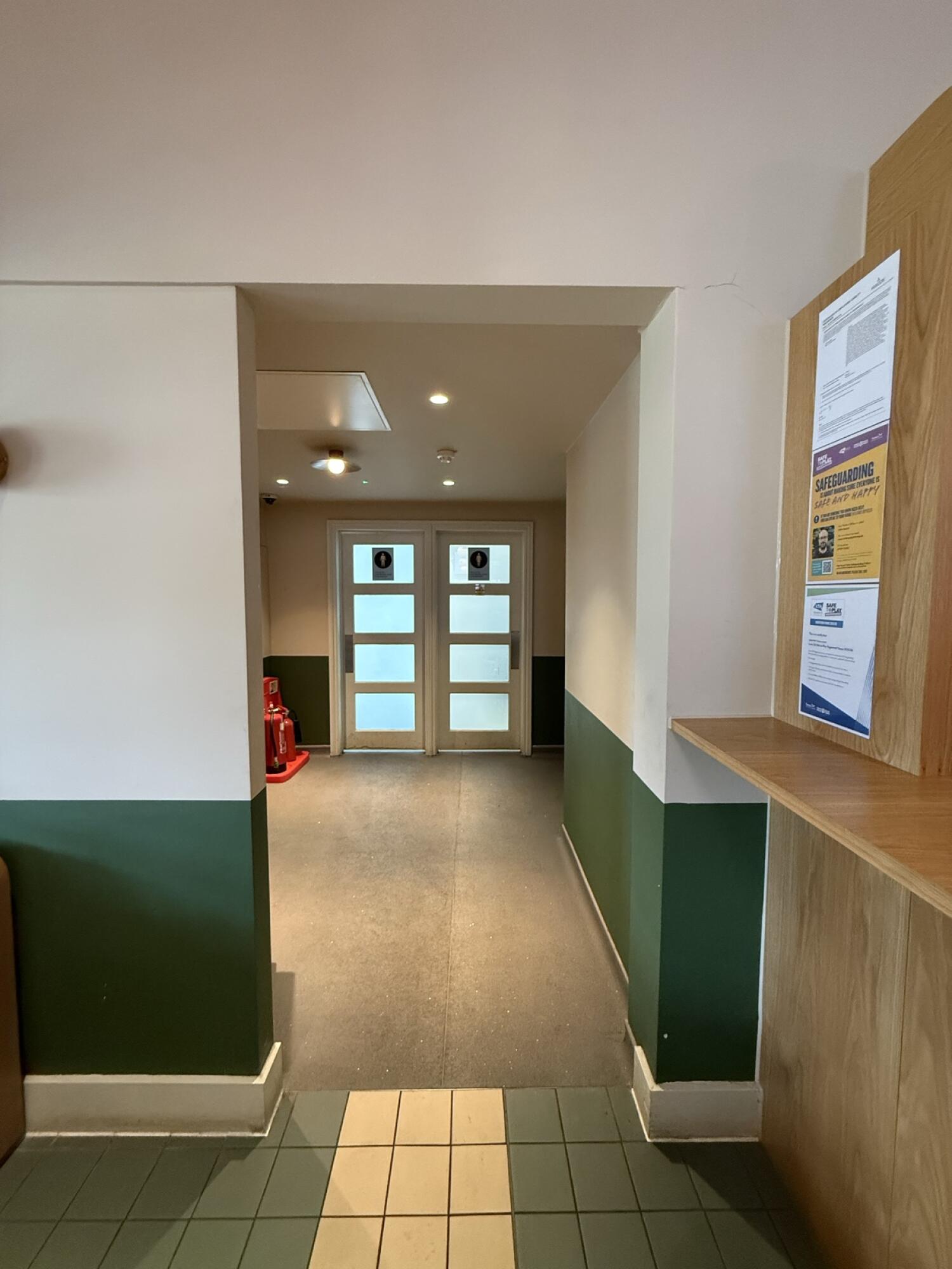 From end of main area facing straight. Open archway ahead. Path leads to non-accessible bathrooms at back.