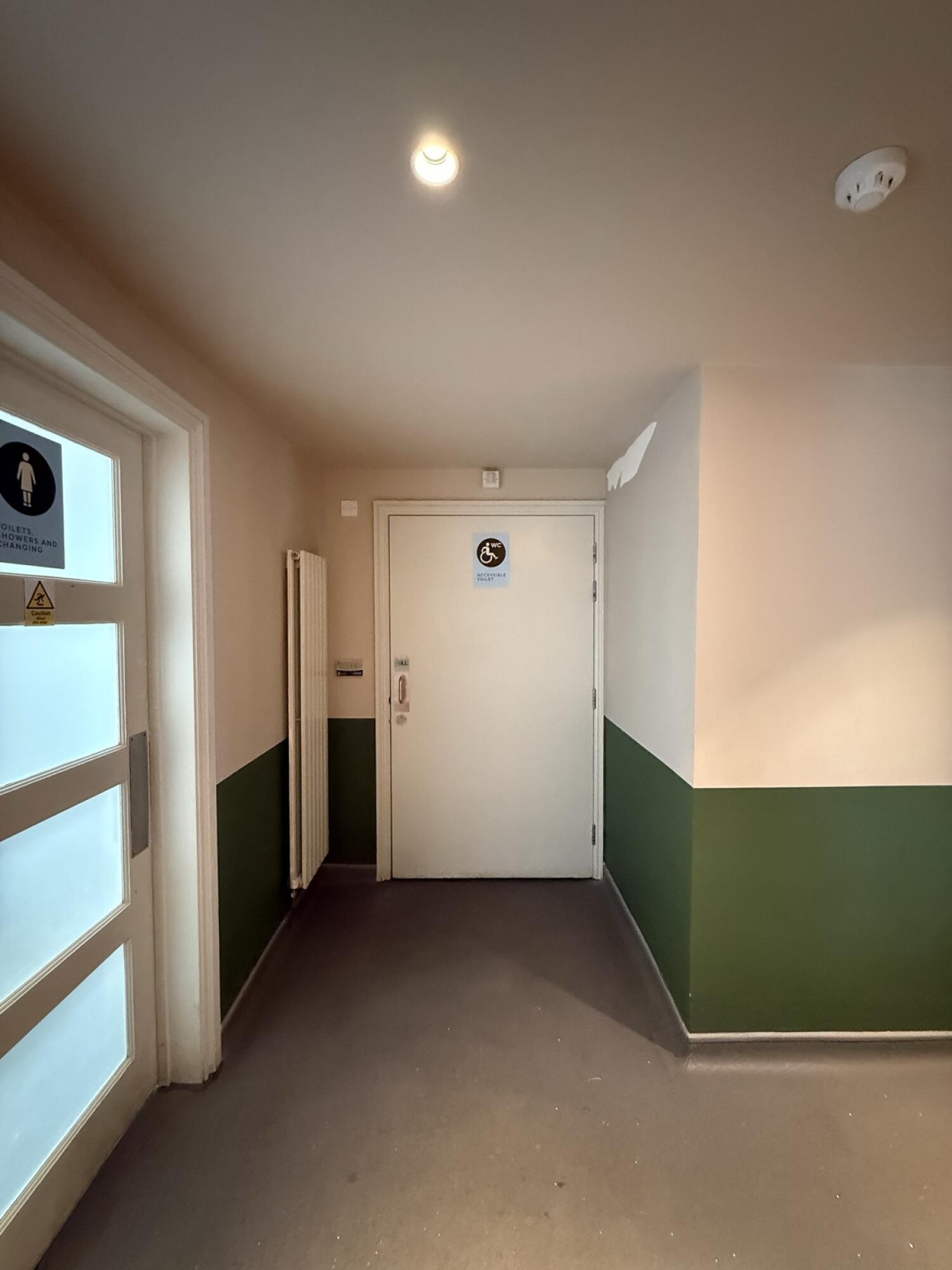 From before bathrooms facing right. Accessible toilet door ahead.