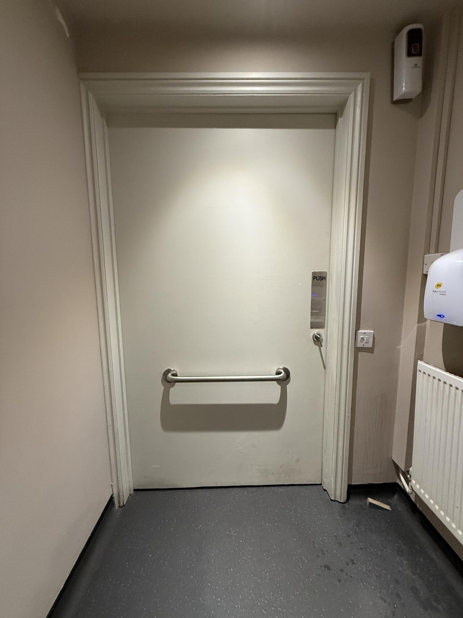 Back of door. Grab rail in centre. Push handle on right to open.