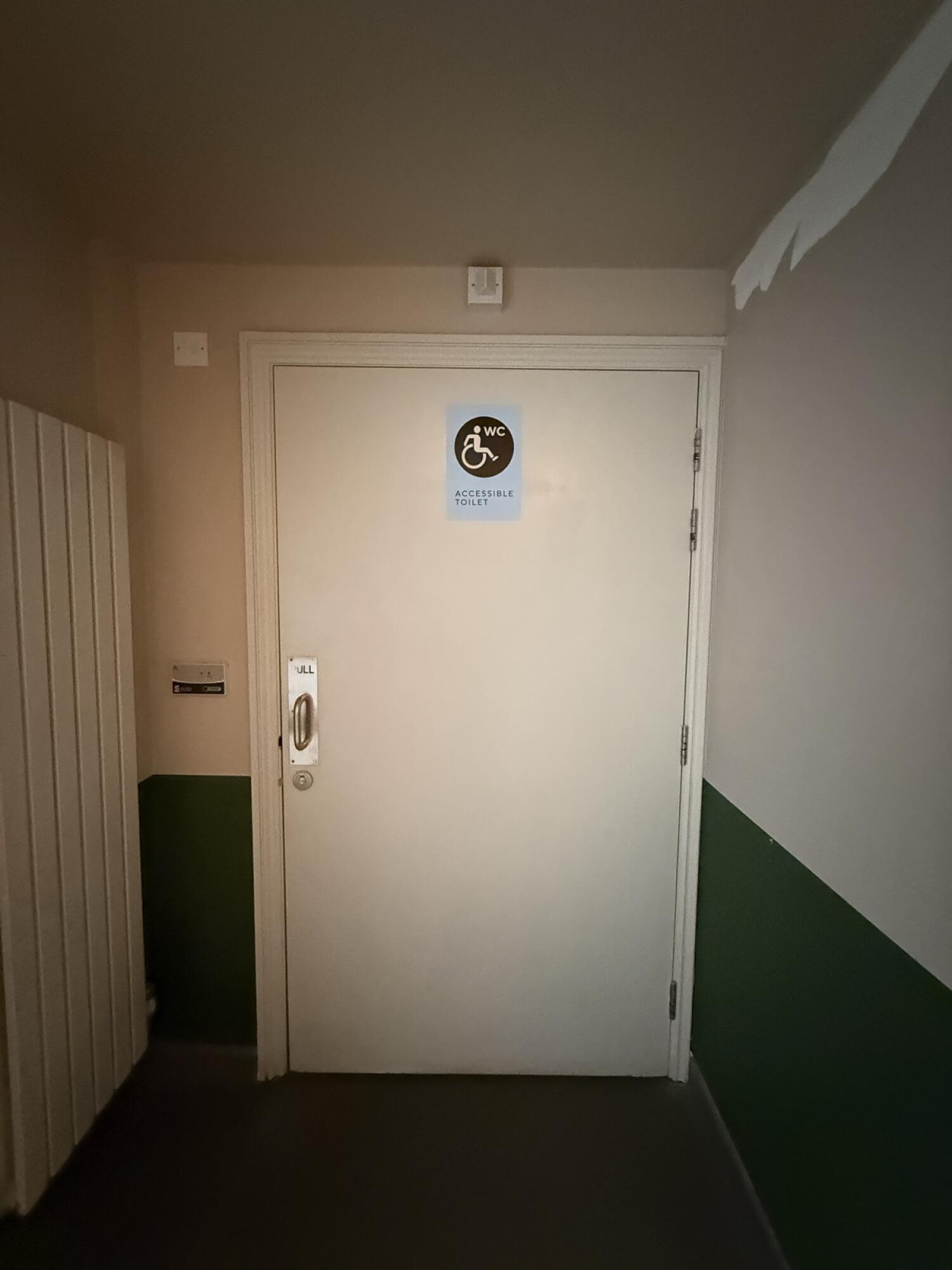 White wooden toilet door ahead. Use handle to open.