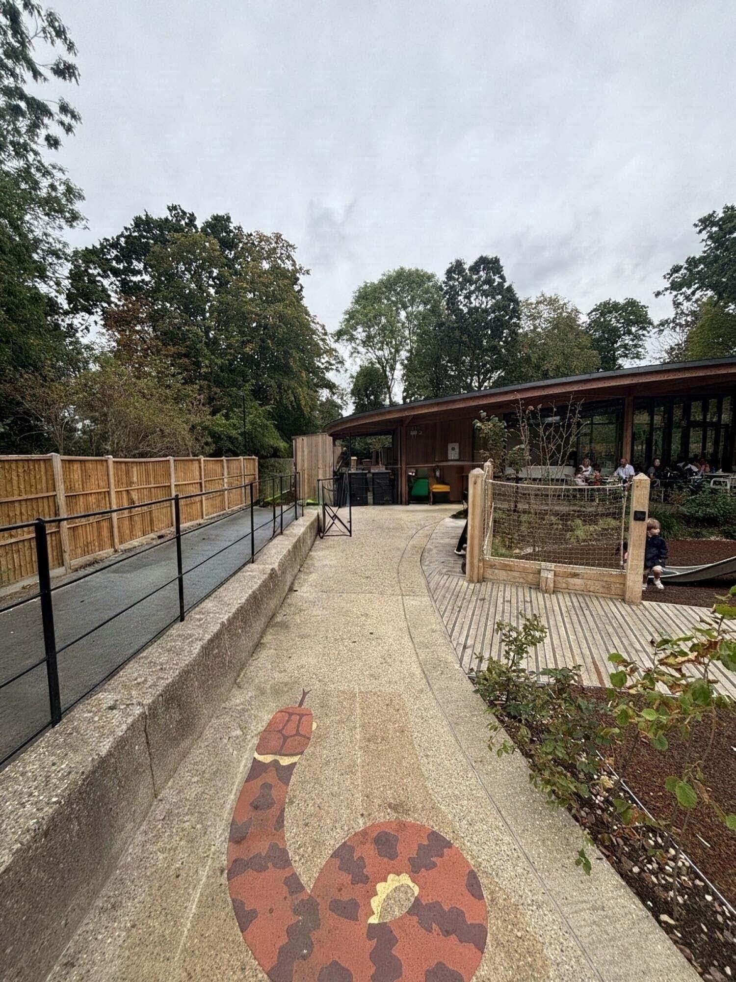 From end of curved path facing straight. Fixed benches along left. Path ahead to buggy parking space at back right.