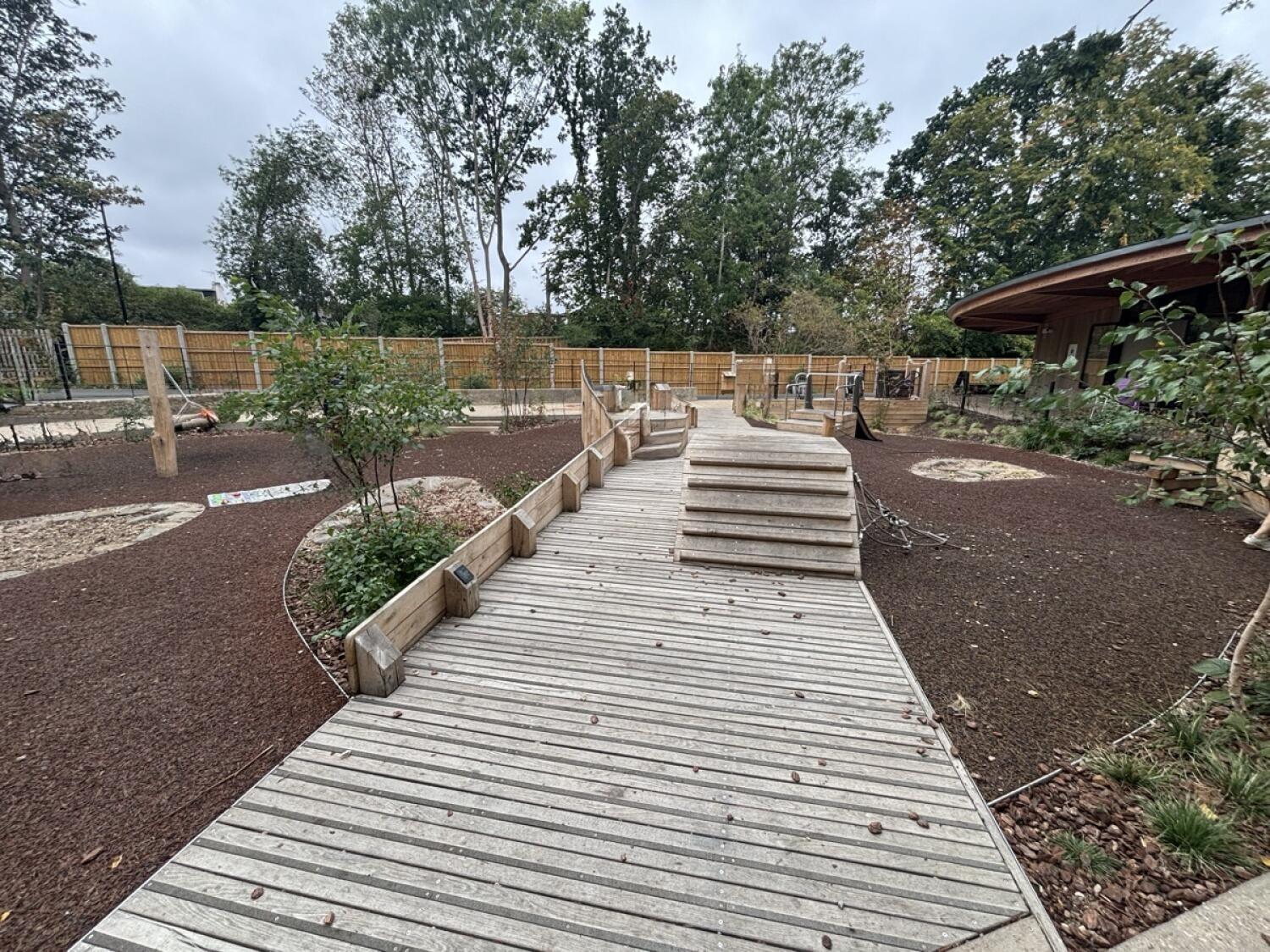 From opening on right facing straight. Wooden path ahead with climbing posts at back right.
