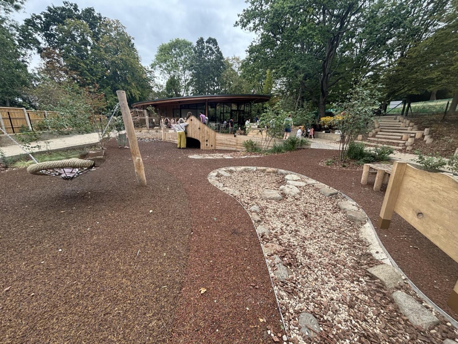 From bottom of steps facing straight. Basket swing on left. Gravel play area on right.